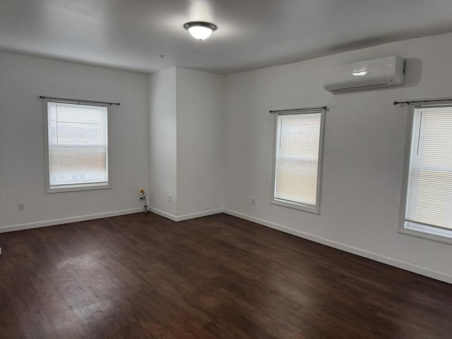 unfurnished room with dark hardwood / wood-style flooring, a wall mounted AC, and a healthy amount of sunlight