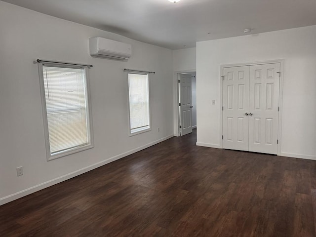 empty room featuring a wall mounted air conditioner and dark hardwood / wood-style flooring