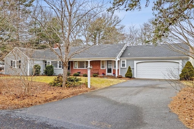 ranch-style house featuring a garage, brick siding, driveway, roof with shingles, and a front lawn