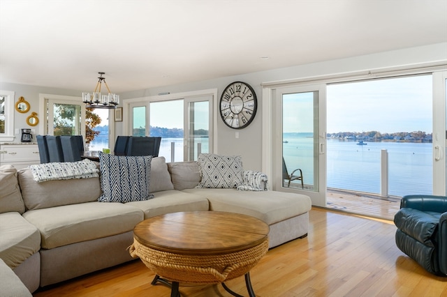 living room with a notable chandelier, a water view, and light wood-type flooring