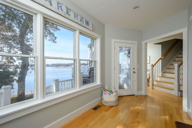 entryway with a water view, wood-type flooring, and a wealth of natural light