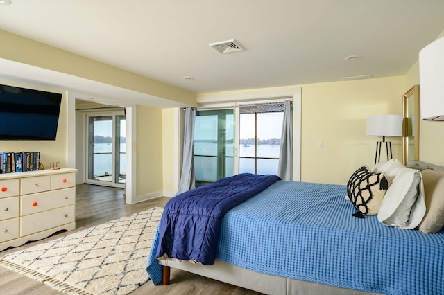 bedroom featuring multiple windows, access to exterior, and hardwood / wood-style flooring