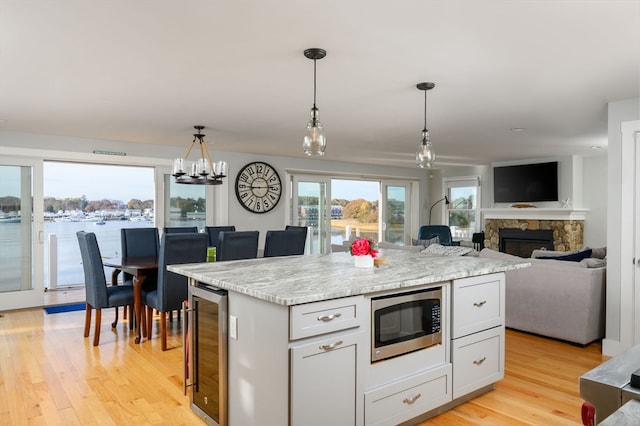 kitchen featuring a kitchen island, stainless steel microwave, light hardwood / wood-style flooring, beverage cooler, and white cabinetry