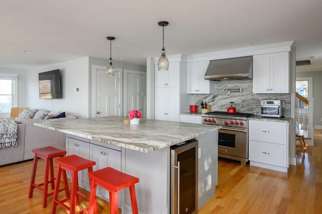 5 Oak Hill Rd, Wareham, MA 02571 - kitchen featuring beverage cooler, designer stove, wall chimney range hood, open floor plan, and light wood finished floors