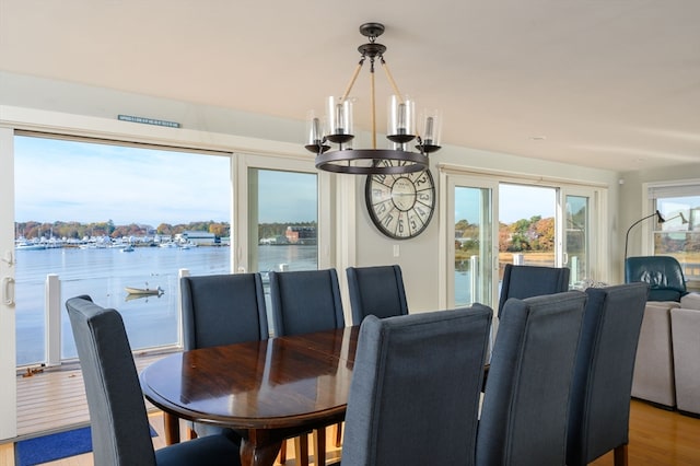 dining room with an inviting chandelier, a water view, and light wood-type flooring