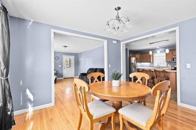 dining room with an inviting chandelier, sink, and light wood-type flooring