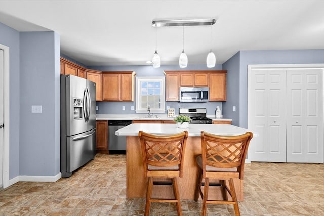 kitchen with sink, stainless steel appliances, a center island, a kitchen breakfast bar, and decorative light fixtures