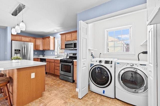 kitchen featuring sink, appliances with stainless steel finishes, hanging light fixtures, a kitchen breakfast bar, and separate washer and dryer