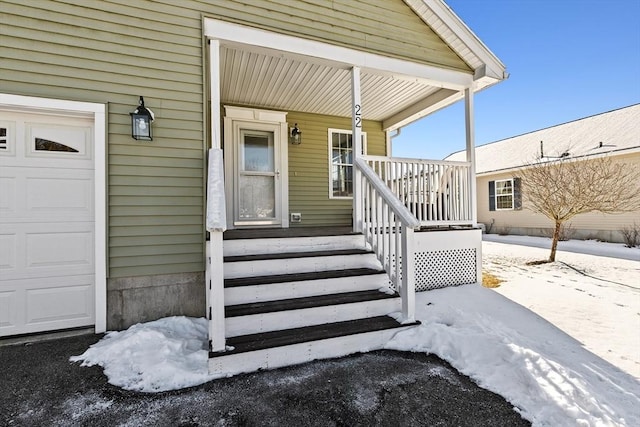 snow covered property entrance with a garage