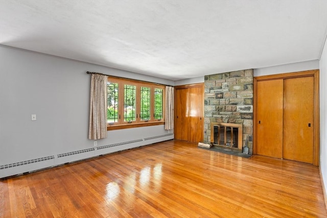16 Sheldon Ave, Easthampton, MA 01027 - unfurnished living room with a baseboard heating unit, light wood-style flooring, and a stone fireplace