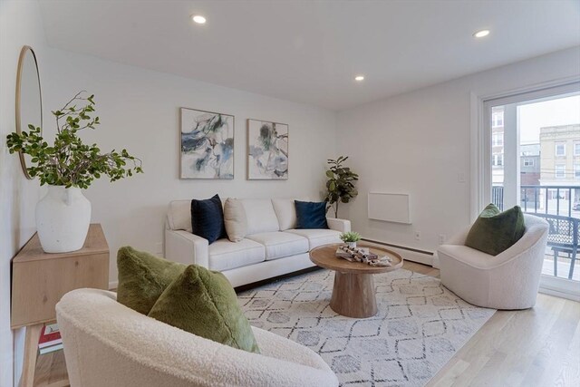 living area with light wood-style floors, a baseboard radiator, baseboards, and recessed lighting
