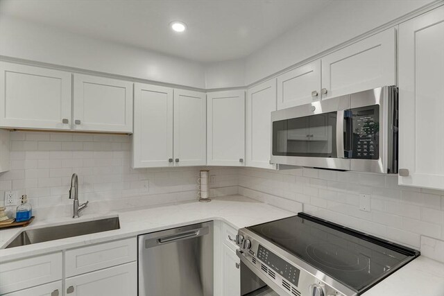 kitchen featuring white cabinets, appliances with stainless steel finishes, a sink, and tasteful backsplash