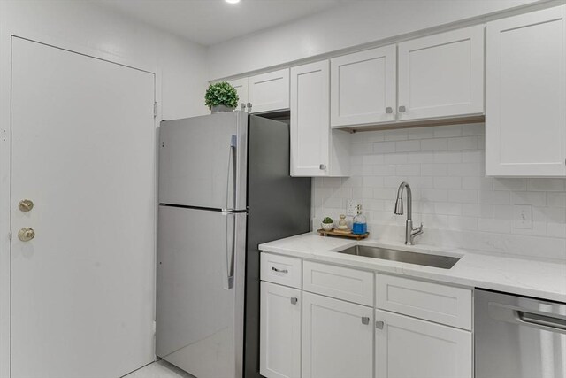 kitchen featuring a sink, appliances with stainless steel finishes, decorative backsplash, and white cabinetry