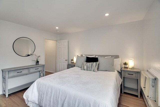 bedroom featuring recessed lighting, a wall unit AC, and wood finished floors