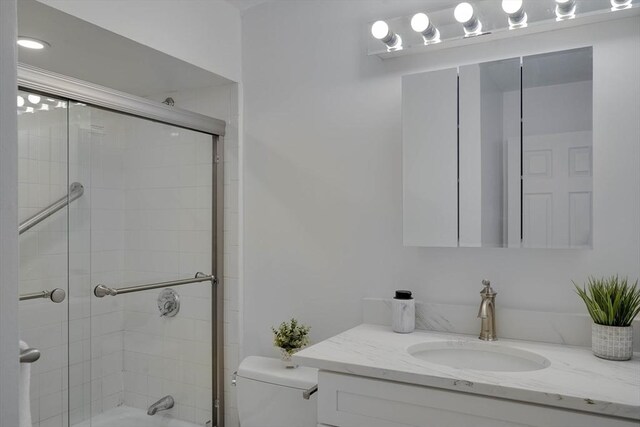 bathroom with vanity, enclosed tub / shower combo, and toilet