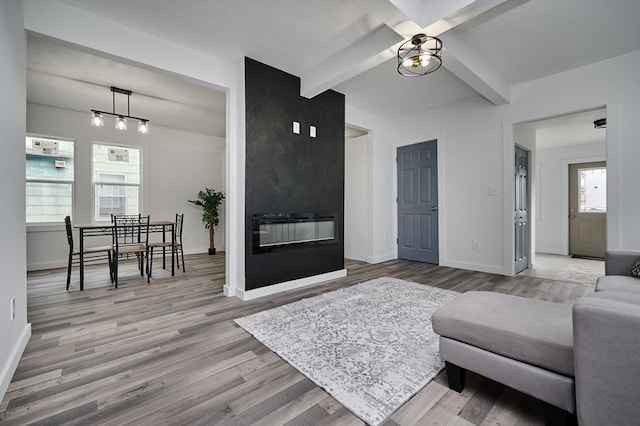 living room with beamed ceiling, a healthy amount of sunlight, and light wood-type flooring