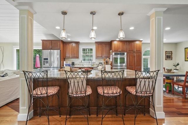6 Lous Dr, Dudley, MA 01571 - kitchen with stainless steel appliances, decorative columns, decorative backsplash, stone counters, and brown cabinetry