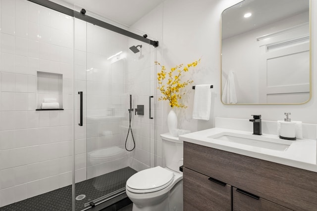 bathroom with a shower with shower door, vanity, and toilet