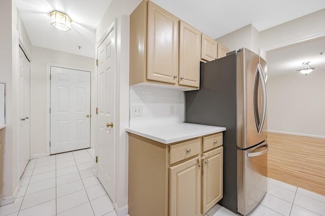 kitchen with freestanding refrigerator, light tile patterned floors, cream cabinetry, and light countertops