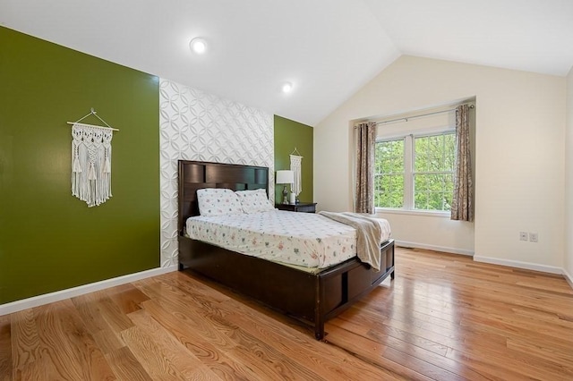 bedroom with an accent wall, baseboards, wood finished floors, and vaulted ceiling