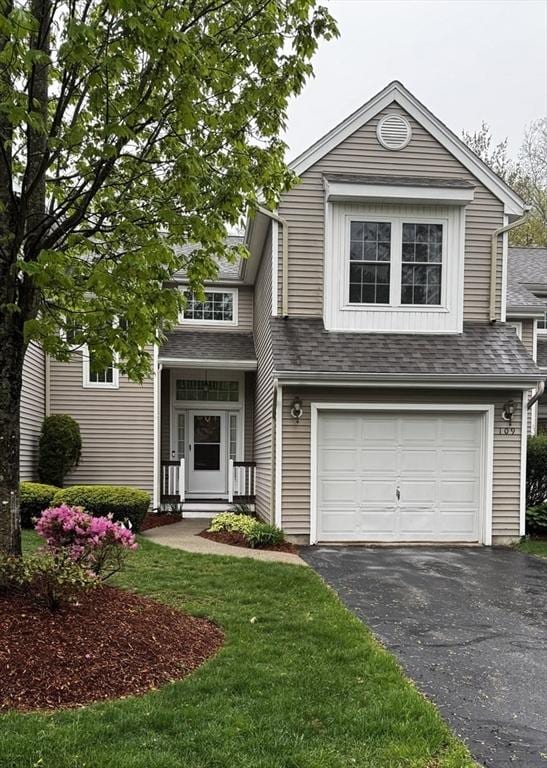 view of front of house featuring asphalt driveway, an attached garage, a front yard, and a shingled roof
