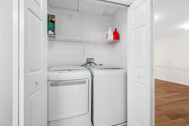 clothes washing area featuring washing machine and clothes dryer and wood finished floors