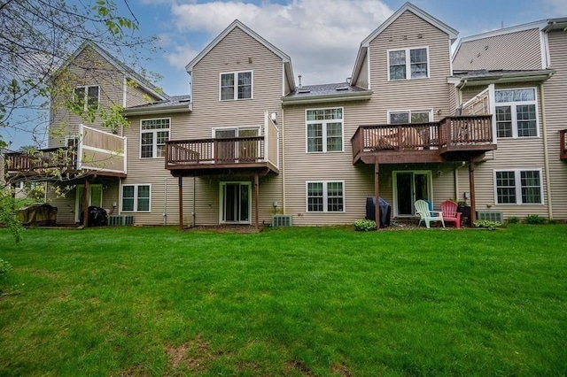back of house featuring a yard, a deck, and a shingled roof