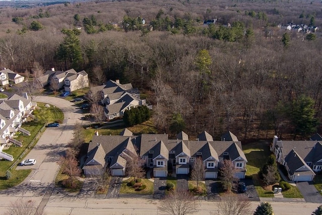 aerial view of property and surrounding area featuring nearby suburban area and a heavily wooded area
