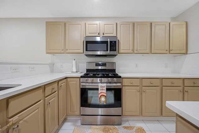 kitchen featuring appliances with stainless steel finishes, light countertops, light brown cabinetry, and decorative backsplash