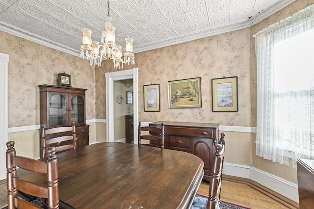 dining area with crown molding, light hardwood / wood-style floors, and a notable chandelier