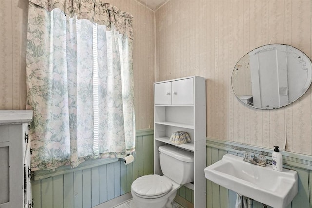 bathroom featuring wooden walls, sink, and toilet