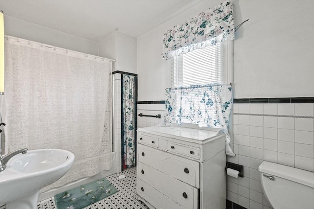 full bathroom featuring sink, shower / bath combination with curtain, toilet, and tile walls