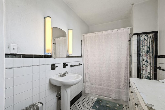 bathroom featuring a textured ceiling, sink, shower / bath combo, and tile walls