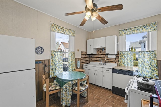 kitchen with white appliances, ceiling fan, sink, dark tile patterned flooring, and white cabinetry