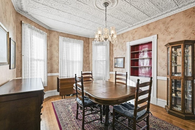 dining area with a notable chandelier, wood-type flooring, and ornamental molding