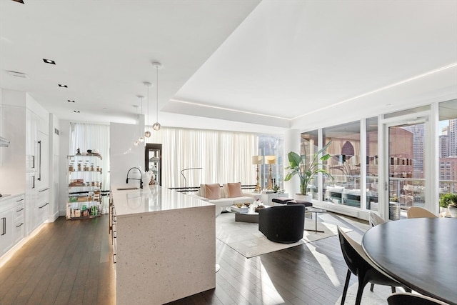 kitchen featuring pendant lighting, a kitchen island with sink, dark hardwood / wood-style flooring, and white cabinetry