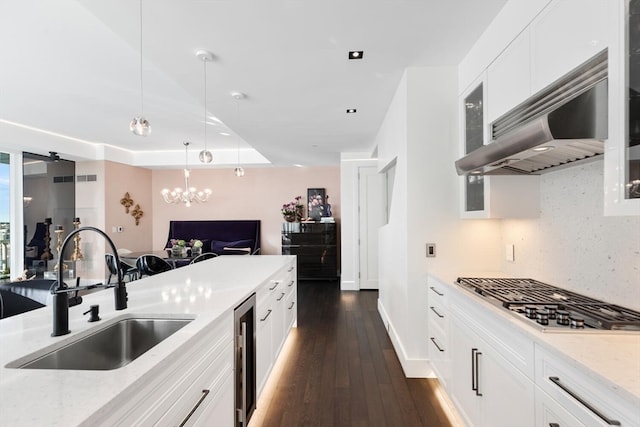 kitchen with dark hardwood / wood-style floors, stainless steel gas stovetop, sink, backsplash, and white cabinetry