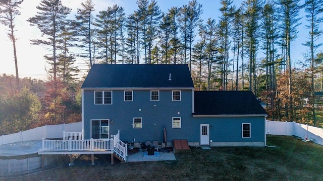 rear view of house featuring a wooden deck and a lawn