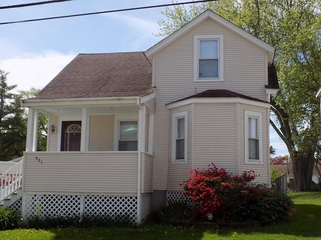 view of front of home with roof with shingles, a porch, and a front lawn