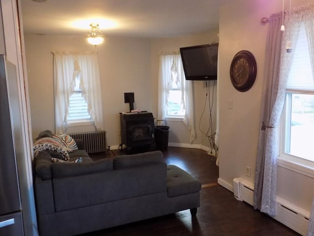 living area featuring radiator, a wood stove, plenty of natural light, and dark wood finished floors
