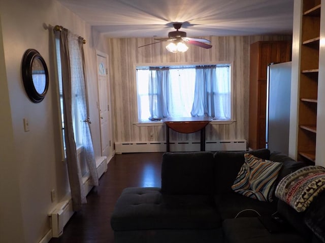 living area featuring a baseboard radiator, ceiling fan, dark wood-style floors, and baseboards