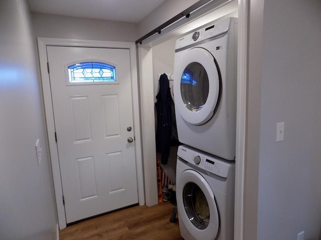 clothes washing area featuring estacked washer and dryer and wood finished floors