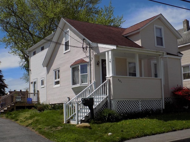 view of front facade featuring a front lawn, roof with shingles, and stairway