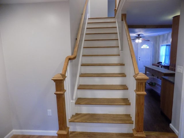 stairway with wood finished floors, a ceiling fan, and baseboards