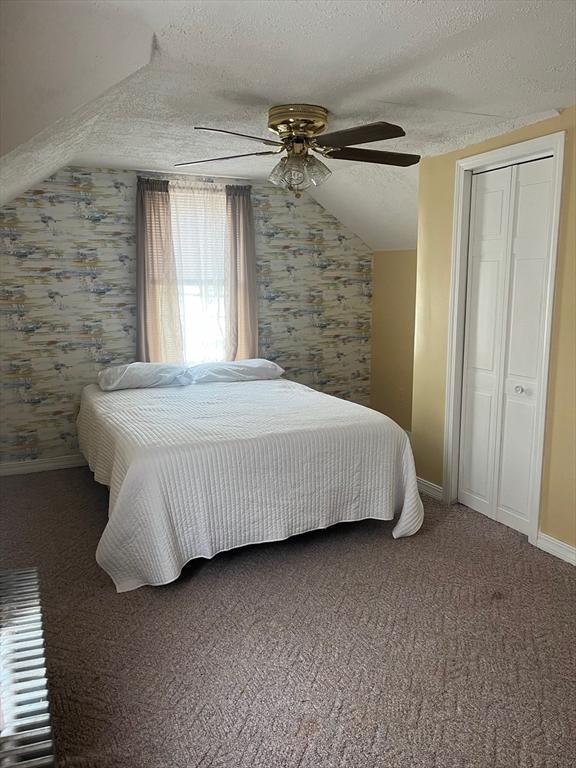 carpeted bedroom with a textured ceiling, lofted ceiling, a ceiling fan, and baseboards
