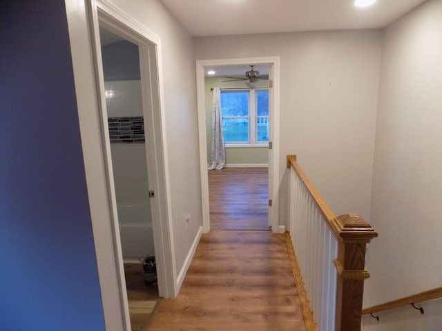 hallway featuring an upstairs landing, wood finished floors, and baseboards