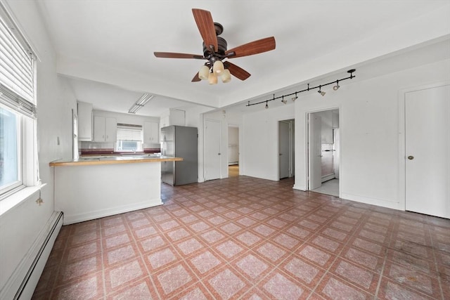 unfurnished living room featuring light floors, baseboard heating, ceiling fan, and track lighting