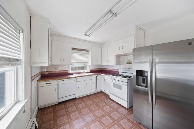 kitchen featuring a sink, white appliances, light floors, decorative backsplash, and white cabinets