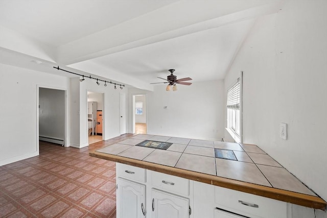 kitchen with a ceiling fan, tile patterned floors, white cabinetry, tile countertops, and a baseboard radiator