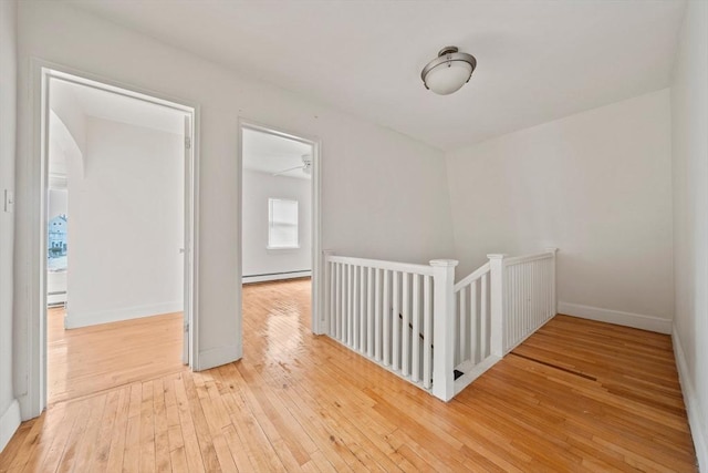 unfurnished room featuring baseboards, baseboard heating, and hardwood / wood-style flooring